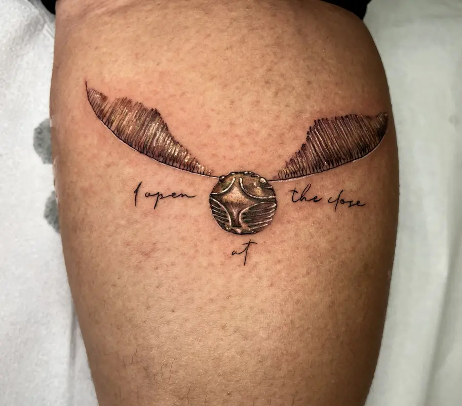 Esfera alada tipo amuleto con el texto “open at the close”, blackwork.