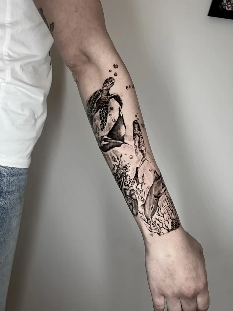 Composición marina con tortuga, pingüino, buceador, tiburón y coral en antebrazo.